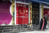 Des femmes et des enfants devant un salon de beauté du quartier de Shahr-e Naw à Kaboul le 4 juillet 2023. Ces salons devront tous fermer d'ici un mois sur décision des autorités talibanes, une mesure qui renforce la mise à l'écart des femmes de la vie publique en Afghanistan.