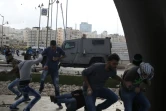 Des Palestiniens lanceurs de pierre se mettent à couvert alors que les forces de sécurité israéliennes tirent des balles en caoutchouc depuis un véhicule, le 8 octobre 2015 à Ramallah