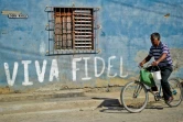 Un Cubain passe à bicyclette devant un graffiti en hommage à Fidel Castro, le 
12 août 2014 à La Havane