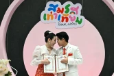 Ploynaplus Chirasukon (gauche) et Kwanporn Kongpetch posent après avoir obtenu leur certificat de mariage, le 23 janvier 2025 à Bangkok