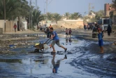 Des Palestiniens traversent une rue inondée à Deir el-Balah, dans le centre de la bande de Gaza, le 23 juillet 2024