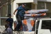 Des travailleurs déchargent d'une camionnette les aides pour les déplacés libanais dans une école transformée en refuge à Tyr, dans le sud du Liban, le 19 octobre 2023