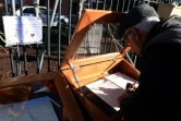 Un homme signe le registre de condoléances de la mairie de Saint-Féliu-d'Avall le 16 décembre 2017