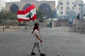 Un homme porte un drapeau libanais lors d'une manifestation, le 8 août 2020 à Beyrouth, pour demander des comptes à la classe politique après la terrible explosion ayant dévasté une partie de la capitale et fait plus de 150 morts