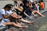 Des touristes se rafraîchissent dans un bassin près du Louvre à Paris, le 26 juin 2019 