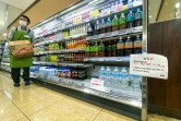 Une affiche (g) indique "l'eau en bouteille est rationnée, avec un plafond d'une caisse (six bouteilles) par client" dans un supermarché du district de Sumida, le 10 août 2024 à Tokyo