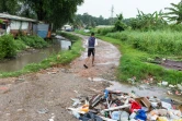 Un jeune homme marche sous la pluie dans le bidonville "la Matine" de Cayenne le 6 avril 2017