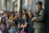 Un militaire vénézuélien surveille ceux qui font la queue devant la banque centrale de Caracas pour échanger leurs billets de 100 bolivars, le 16 décembre 2016