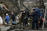 Une femme porte un chien en traversant un pont détruit à Irpin (Ukraine) pendant des bombardements, le 5 mars 2022
