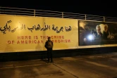 Un combattant irakien du Hachd al-Chaabi debout devant une immense pancarte anti-américaine à Bagdad, le 2 janvier 2021 