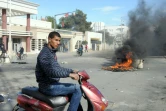 Un jeune Tunisien passe devant des pneus brûlés lors de heurts avec la police, le 20 janvier 2016 à Kasserine