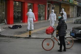 Des membres des services de secours s'approchent du corps d'un homme mort dans la rue à Wuhan, le 30 janvier 2020 en Chine