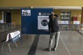 Pose d'une affiche sur un isoloir, dans un bureau de vote à Santiago du Chili, le 14 mai 2021