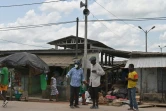 Des habitants dans une rue du village d'Azaguié Ahoua, près d'Abidjan, où des hauts-parleurs diffusent des messages sur le coronavirus, le 27 mars 2020 en Côte d'Ivoire