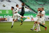 Le Suisse Kevin Mbabu (C) marque de la tête pour Wolfsbourg devant des tribunes vides recouvertes de bâches contre l'Eintracht Francfort le 30 mai 2020 à Wolfsbourg