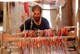 Un homme tisse un tapis traditionnel dans une échoppe du marché de Hilla, le 12 octobre 2017 en Irak