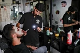 Un coiffeur utilise la lumière de son téléphone portable pour s'éclairer dans son salon, le 20 août 2021 à Beyrouth, au Liban