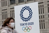 Une passante portant un masque, devant le logo des Jeux olympiques 2020, à Tokyo le 23 avril 2020