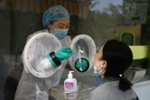 Une technicienne (g) prélève un échantillon sur une employée de la société de biotechnologie chinoise Coyote qui fabrique le Flash 20, une machine de dépistage rapide du coronavirus
