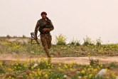 Un combattant des Forces démocratiques syriennes court avec son arme lors d'une opération contre le groupe Etat islamique, près de Baghouz en Syrie, le 14 février 2019