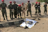 Des policiers yéménites observent le corps d'une victime d'une attaque contre une caserne, près d'Aden (Yémen), revendiquée par les rebelles Houthis, le 1er août 2019