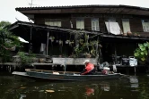 Nopadol, postier, distribue des lettres et colis aux habitants vivant sur les bords d'un canal dans la province de Bang Khun Thian, près de Bangkok en Thaïlande, le 17 juillet 2017