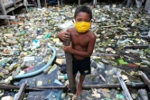 Un enfant pataugeant dans des déchets flottant porte un masque de protection contre le coronavirus, à Manaus, au Brésil, le 26 mai 2020