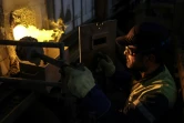 Un employé surveille l'intérieur d'un four pendant le processus de fabrication de bouteilles en verre à la Verrerie d'Albi, le 27 avril 2023 à Saint-Juéry, dans le Tarn