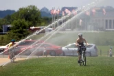 Des cyclistes roulent sous les jets d'une fontaine à Washington le 19 juillet 2019