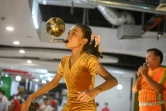 Han Myint Mo tient en équilibre une balle dorée sur la lame d'un couteau, le manche entre ses dents, lors d'un spectacle dans un centre commercial,  le 5 juillet 2022 à Rangoun, en Birmanie