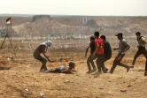 Des Palestiiens viennent en aide à un manifestant blessé lors d'affrontements avec les forces israéliennes près de la frontière avec la bande de Gaza, à l'est de la ville de Gaza, le 13 avril 2018 
