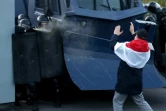 Un manifestant face aux policiers anti-émeute pendant une manifestation à Minsk, le 25 octobre 2020