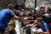 Des déplacés palestiniens viennent chercher à manger dans un point de distribution alimentaire gratuite à Jabalia, dans la bande de Gaza, le 19 mai 2025 