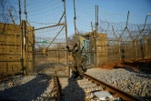 Un soldat sud-coréen ouvre une barrière pour dégager des rails conduisant à la Corée du Nord, le 30 novembre 2018 à Paju, dans la zone démilitarisée séparant les deux Corées