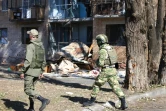 Des volontaires passent devant un immeuble touché par des frappes ukrainiennes, le 16 août 2024 à Koursk, en Russie