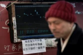 Un boursicoteur explique la volatilité des cours devant son ordinateur à Shanghai, le 25 mars 2018