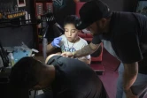 Brandon Burgos, 11 ans, réalise un tatouage sur un client, le 10 novembre 2021 à Puebla, au Mexique