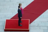 La chancelière allemande Angela Merkel (d) et le président français Emmanuel Macron, écoutant les hymnes nationaux lors d'une rencontre à Berlin le 15 mai 2017