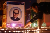 Un fidèle allume une bougie devant un portrait de l'archevêque Oscar Romero, à Ciudad Barrios, sa ville natale, au jour de sa canonisation le 14 octobre 2018 
