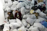 Des bénévoles d'un centre d'aide humanitaires se reposent au milieu de sacs de vêtements pour les réfugiés, à Lviv (Ukraine), le 19 mars 2022