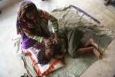 Une femme déplacée et son enfant, qui ont fui les zones touchées par les inondations dans la province de Sindh, se reposent dans une école à Karachi, le 27 août 2022