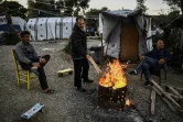 Des hommes se réchauffent autour d'un feu de bois dans le camp de réfugiés de Moria sur l'île grecque de Lesbos, le 19 mars 2019