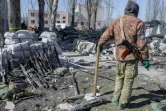 Un soldat ukrainien garde des fusils de soldats morts et blessés près de la caserne touchée la veille par des roquettes russes, à Mykolaïv, dans le sud de l'Ukraine, le 19 mars 2022.