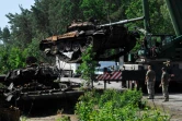 Des soldats ukrainiens récupèrent un char russe détruit à Dmytrivka, village de la région de Kiev, le 20 juin 2022