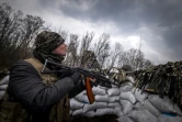 Un militaire ukrainien tient un fusil dans une tranchée près de Kharkiv le 31 mars 2022