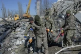 Des soldats ukrainiens évacuent l'un des leurs, tué dans le bombardement d'un école militaire à Mykolaiv, le 19 mars 2022