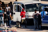 Vingt-sept migrants mineurs non-accompagnés, secourus par le navire de l'ONG espagnole Proactiva Open Arms, sont conduits vers des véhicules de la police italienne avant de quitter le port de Lampedusa où ils ont débarqué le 17 août 2019