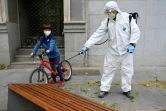 Un enfant et un employé chargé de la désinfection des rues à Madrid le 28 avril 2020