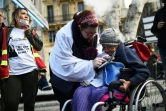 Une femme assiste une personne âgée, lors d'une manifestation à Paris, le 30 janvier 2018