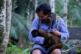 Un singe laineux et un bébé dans les bras de Jhon Jairo Vasquez, fondateur du refuge de Maikuchiga, le 18 novembre 2020 près de Leticia, en Amazonie colombienne 